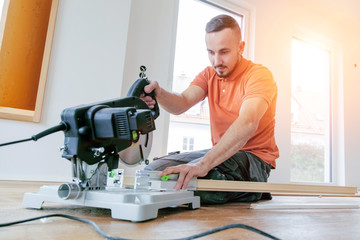 craftsman cuts wood plank with the chop saw on the construction