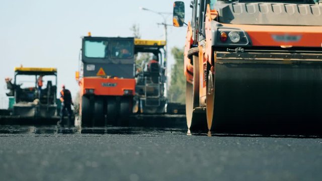 Road rollers work on a road during paving.