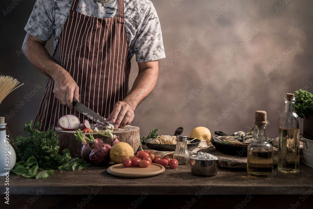 Wall mural handsome bearded cheef cook prepairing spaghetti on a kitchen.