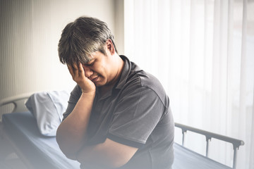 An Asian middle aged man Sitting on a patien's bed Is suffering from stress From their own illness the cause is obesity Causing diabetes Grease and clogging, to health care and insurance concept.