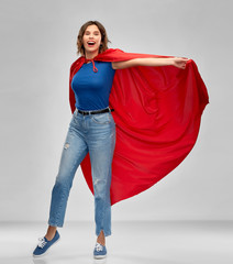 women's power and people concept - happy woman in red superhero cape over grey background
