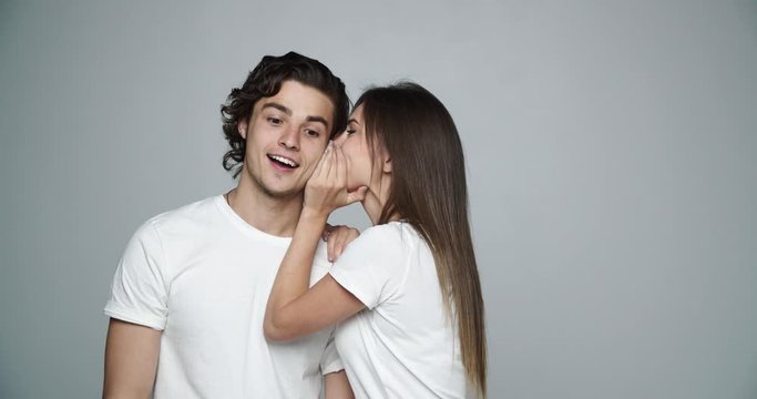 Young woman tell secret to her man isolated