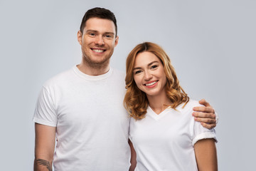 Fototapeta premium relationships and people concept - portrait of happy couple in white t-shirts over grey background