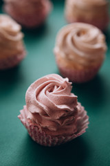 pink muffins with cream on a dark green background