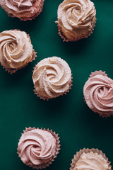 pink muffins with cream on a dark green background