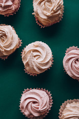 pink muffins with cream on a dark green background
