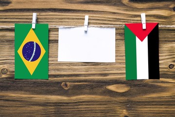 Hanging flags of Brazil and Palestine attached to rope with clothes pins with copy space on white...