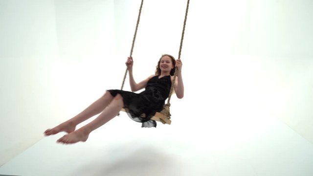 A little girl is swinging on a swing with a teddy bear.