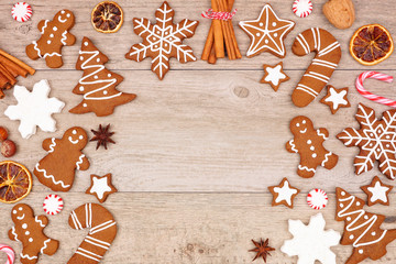 Christmas gingerbread cookies, candy and baking items. Above view arched frame on a wood background with copy space.