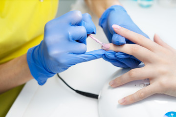 Nail care. Manicure in the salon. The master manicures the girl, beauty and health. Manicure process. Master in mask and gloves. Nail polish.