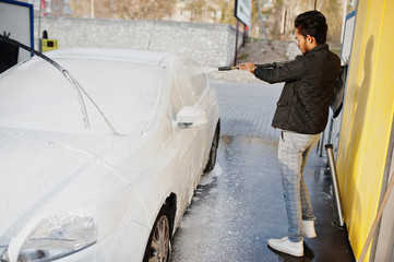 South asian man or indian male washing his white transportation on car wash.