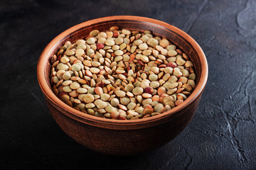 Lentils in a clay vessel on a black concrete background