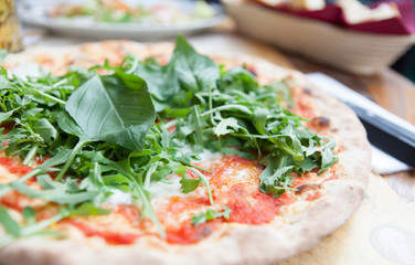 Close up of italian pizza with rucola and basil