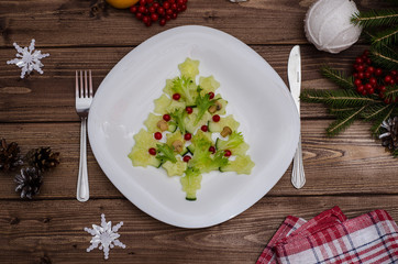Edible Christmas tree made of vegetables for the festive New Year and Christmas table on a wooden background. Idea for decorating holiday dishes. How nice to serve vegetables and salad.