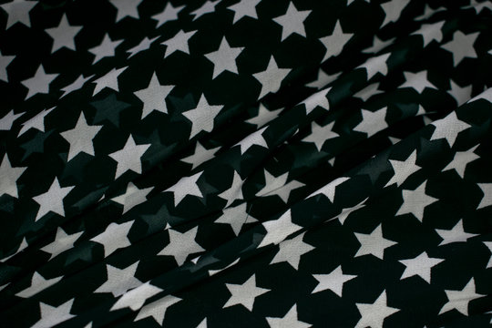 Fabric with the image of white stars on a black background, slightly crumpled.