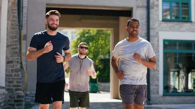 fitness, sport and healthy lifestyle concept - smiling young men or male friends running outdoors