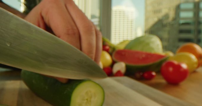 Close up of cutting a cucumber, cooking process, tasty and vibrant image, sharp knife, chopping a cucumber, cityscape background