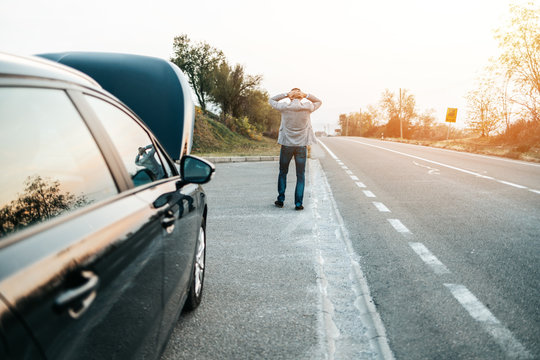 Car Issue Breakdown Or Engine Failure. Elegant Middle Age Man Waiting For Towing Service For Help Car Accident On The Road. Roadside Assistance Concept.