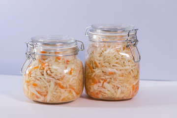 Sauerkraut, fermented cabbage in a glass jar on a gray background