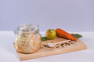 Sauerkraut, fermented cabbage in a glass jar on a gray background