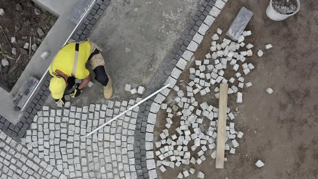 Granite Brick Paving Worker. Contractor Building Residential Garden Path. Aerial Footage.