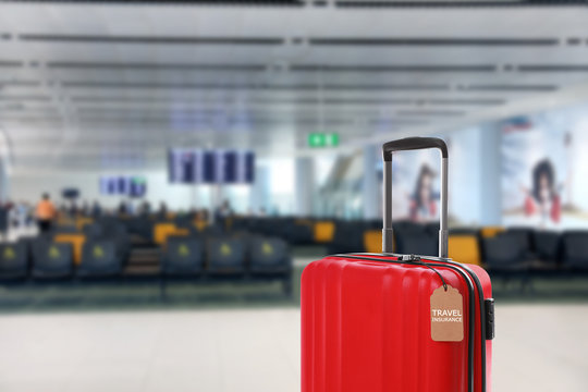 Red Suitcase With TRAVEL INSURANCE Label In Airport Terminal