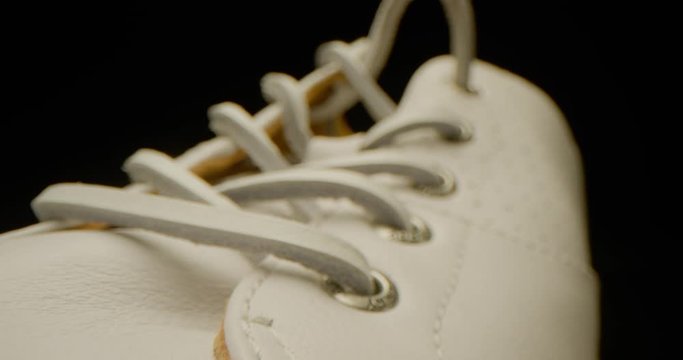 White leather sneakers macro shot, leather laces, dramatic look, red epic, slow motion, black background 