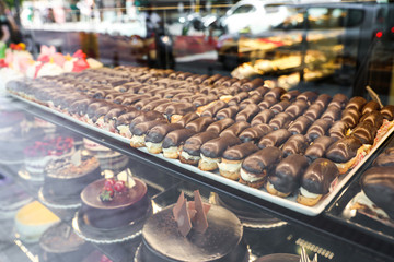 Different delicious cakes on display in cafe, view through window