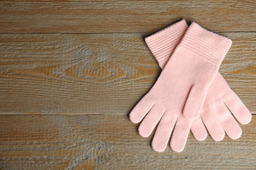 Stylish pink gloves on wooden background, top view with space for text. Autumn clothes