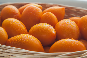 many ripe yellow tomatoes with drops of water close-up in backlight