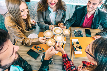 Top view of happy friends toasting cappuccino drink at coffee shop restaurant - Millennial people group having fun on breakfast together at fashion cafe bar - Friendship concept on vivid warm filter