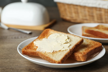 Crispy toasted bread with butter on wooden table, closeup