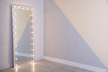 Large mirror with lamps near color wall. Space for text