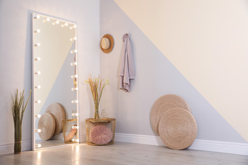 Large mirror with lamps in stylish room interior