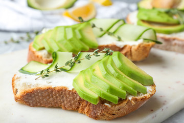 Tasty sandwiches with avocado and cucumber on table, closeup