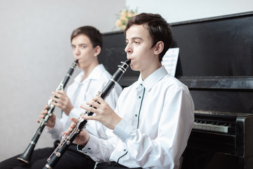 A boys with a clarinet plays music.children are engaged in music at the music school hands on a wind musical instrument close up - obrazy, fototapety, plakaty