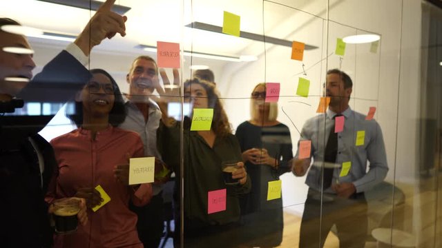 Smiling businesspeople brainstorming together with sticky notes in an office