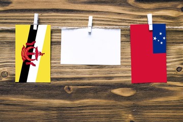 Hanging flags of Brunei and Samoa attached to rope with clothes pins with copy space on white note...
