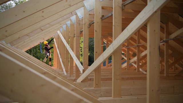 Wooden Roof Frame Construction and Caucasian Contractor Worker in His 30s. Industrial Theme.