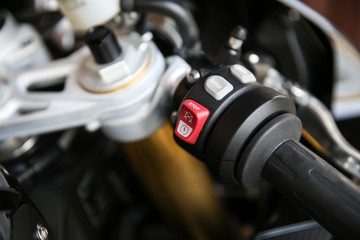 part of a sport bike close up. red button of start or stop engine of motorcycle. buttons on the right handle of superbike's handlebar
