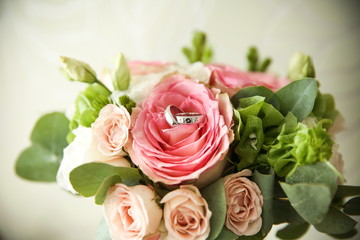 background of two wedding rings in a rose bud close up