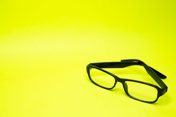 Broken bow near glasses on yellow background