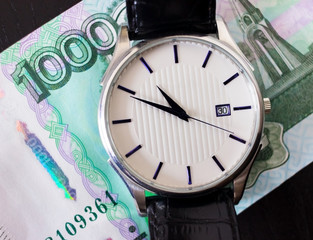 'Time - money' concept. Russian rouble bill and men's watch. 1000 ruble banknote