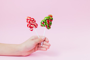 View of two candies in the form of a Christmas tree in his hand on pink paper. Festive Christmas background