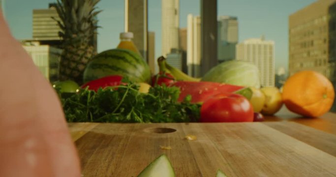 Sliding near knife while cutting apple, composition of fruits and vegetables, downtown LA on background, slow motion, macro shot on Red Weapon Helium 8k
