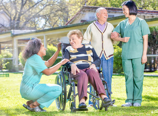 Female doctor reassuring elderly retired people in the hospital garden