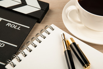 movie clapper, cup of coffee and fountain pen diary