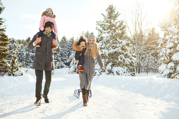 Happy family sledding in the park in winter.