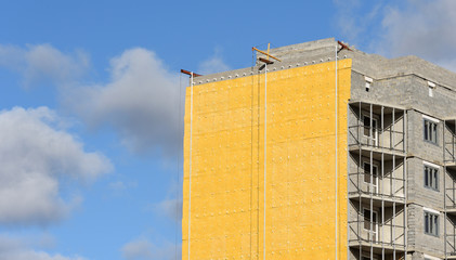 Construction of a high residential building and insulation of its external wall with special heat-insulating material. Wall with thermal insulation against the blue sky