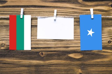 Hanging flags of Bulgaria and Somalia attached to rope with clothes pins with copy space on white...